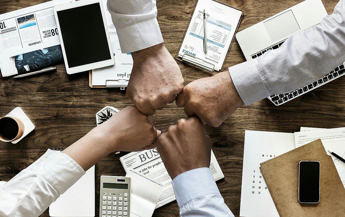 Hands of business partners forming a circle over documents as a sign of cooperation