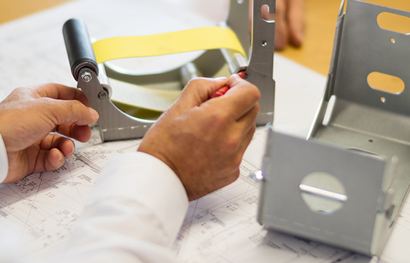 Techniker prüft ein Gehäusebauteil eines textilen Brandschutzsystems anhand einer Konstruktionszeichnung