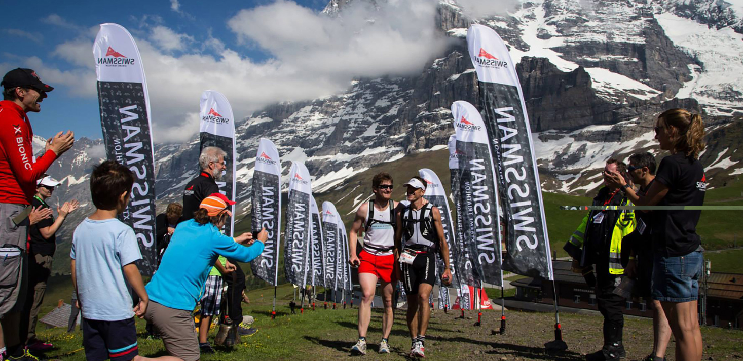 Teilnehmer des Swissman Triathlons im Ziel vor Bergkulisse