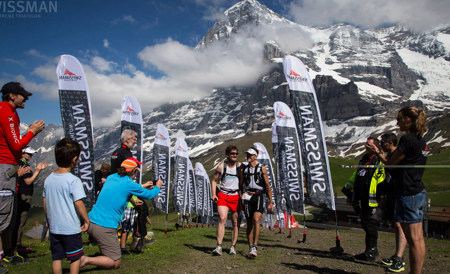 Swissman triathlon participants at the finish in front of a mountain backdrop